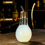 Kreative Glühbirne mit Milchfüllung und Strohhalm, dekoratives wissenschaftliches Objekt für Zuhause oder Büro, inspiriert von wissenschaftlicher Ästhetik.