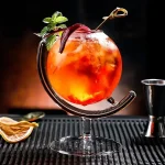 Bunter Sommercocktail in einem stilvollen Glas mit Minzblatt und Zitrusfrucht, perfekt für heiße Tage.