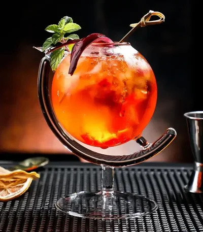 Bunter Sommercocktail in einem stilvollen Glas mit Minzblatt und Zitrusfrucht, perfekt für heiße Tage.