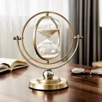 Elegante Sanduhr mit goldfarbenem Rahmen und klarer Glaskugel, die feinen Sand enthält, auf einem Holzschreibtisch. Perfekt als wissenschaftliches Dekor oder stilvolles Accessoire.
