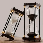 Elegante Sanduhr mit schwarzem Sand, Holzrahmen und goldenen Akzenten, ideal für wissenschaftliche Dekorationen und stilvolle Raumgestaltung.