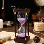 Stilvolle Sanduhr mit schwarzem Rahmen und lila Sand, ideal als Dekoration oder Zeitmesser in modernen Räumen.