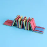Bunte Buchstütze aus Schaumstoffblöcken in verschiedenen Farben, die ein Buch in einer modernen Dekoration halten. Perfekt für Wissenschafts- und Dekorationsliebhaber.