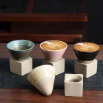 Drei stilvolle Kaffeetassen mit Latte Art, präsentiert auf minimalistischen Keramikständern, ideal für Kaffee- und Dekorationsliebhaber.