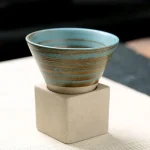 Elegante Porzellan-Schale mit blauen und braunen Streifen, präsentiert auf einem weißen Quaderständer, ideal für wissenschaftliche Dekorationen oder Sammlerstücke.