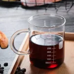 Glas mit dunkler Flüssigkeit und Messskala, ideal für wissenschaftliche Experimente und Dekorationen im wissenschaftlichen Stil.