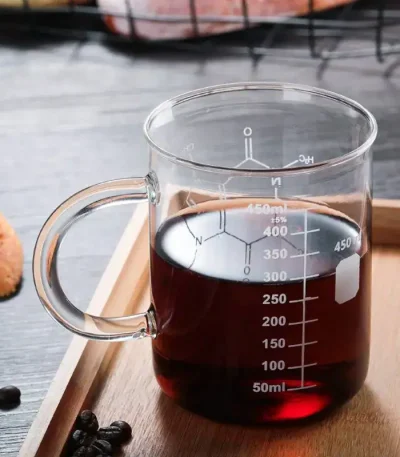 Glas mit dunkler Flüssigkeit und Messskala, ideal für wissenschaftliche Experimente und Dekorationen im wissenschaftlichen Stil.