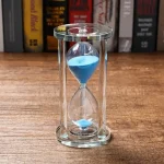 Elegante Sanduhr mit blauer Flüssigkeit in transparentem Glas, ideal für wissenschaftliche Dekorationen und als Lehrmittel.