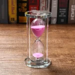 Sanduhr mit rosa Sand in einem transparenten Glasgehäuse.