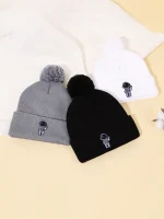 Zwei gestrickte Mützen, eine grau mit Pompon und eine schwarz, sowie eine weiße Mütze mit Wissenschafts-Logo, ideal für kalte Tage.
