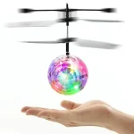 Miniatur-Hubschrauber, der einen schwebenden, bunten Disco-Ball über einer Hand hält, ideal für wissenschaftliche Gadgets und Dekorationen.