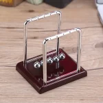 Newton-Wiege mit Metallkugeln auf Holzbasis.