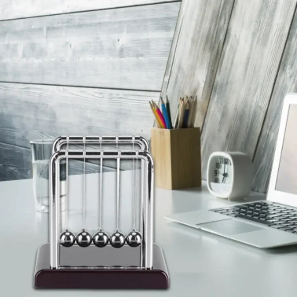 Klassische Newton-Wiege mit fünf Metallkugeln auf einem weißen Tisch, ideal für physikalische Experimente und wissenschaftliche Dekorationen.