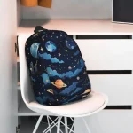 Rucksack mit Weltraummotiv, gestaltet mit Planeten, Sternen und Galaxien, auf einem weißen Stuhl in einem modernen Raum. Perfekt für Science-Fans und Astronomie-Enthusiasten.