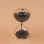 Elegante Sanduhr mit schwarzem Sand in klarer Glasform, ideal für wissenschaftliche Dekorationen und moderne Inneneinrichtung.