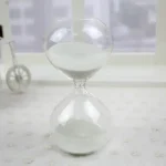Sanduhr aus Glas mit weißem Sand, symbolisiert Zeitmessung und Wissenschaft.