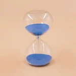 Sanduhr mit blauer Sandfüllung, transparentes Gehäuse, stilvolles Design für Wissenschafts- und Dekorationsliebhaber.