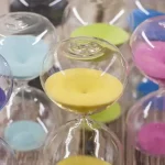 Sanduhr mit buntem Sand, perfekt für wissenschaftliche Dekorationen und Lernzwecke, bietet eine visuelle Darstellung der Zeitmessung in einem stilvollen Design.