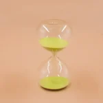 Sanduhr mit grüner Basis und transparentem Glas, ideal als wissenschaftliches Dekor oder Geschenk.