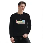 Mann trägt ein schwarzes Sweatshirt mit einem farbenfrohen Periodensystem-Design auf der Vorderseite, ideal für Wissenschafts- und Chemie-Enthusiasten.
