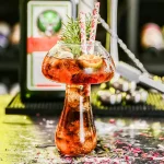 Ein kreativer Getränkespender im wissenschaftlichen Stil mit Glas, Dekorationen und Strohhalmen, ideal für Partys und wissenschaftliche Themenveranstaltungen.