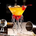 Eleganter Cocktail in einem wissenschaftlich inspirierten Glas mit Tentakeln-Design, gefüllt mit einem bunten Getränk und einer Kirsche, perfekt für Dekoration und Wissenschafts-Themen.