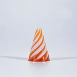 Nahaufnahme eines kleinen, transparenten Konus mit orange-weißen Streifen, der auf weißem Hintergrund steht, geeignet für wissenschaftliche Dekorationen.