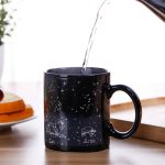 Schwarze Tasse mit Sternbildern von Löwe und Widder, Wasser wird eingegossen, ideal für Astronomie- und Wissenschaftsbegeisterte.
