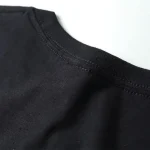 Nahaufnahme eines schwarzen T-Shirts mit Rundhalsausschnitt, Stoffdetails sichtbar, modisches Basic für Alltag und Freizeit.