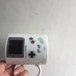Kleine Game Boy Mini-Konsole in der Hand, mit klassischen Steuerungselementen und Bildschirm, ideal für Retro-Gaming-Fans.