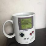 Weiße Tasse in Form eines Game Boy mit Super Mario Land Bildschirm, detailreiche Gestaltung, ideal für Gaming- und Nerd-Fans.