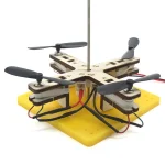 Modell einer kleinen fliegenden Drohne mit Propellern, Sensoren und elektronischen Komponenten auf einer gelben Basis, ideal für wissenschaftliche Demonstrationen.