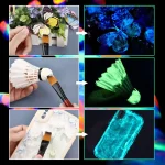Verschiedene wissenschaftliche Objekte, die im Dunkeln leuchten, darunter ein Schmetterling, ein Shuttle-Modell und ein Smartphone, die mit fluoreszierender Farbe bemalt sind.
