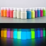 Farbige Fläschchen in einem Farbfächer, beleuchtet im Dunkeln mit fluoreszierender Wirkung, ideal für wissenschaftliche Dekorationen und kreative Projekte.