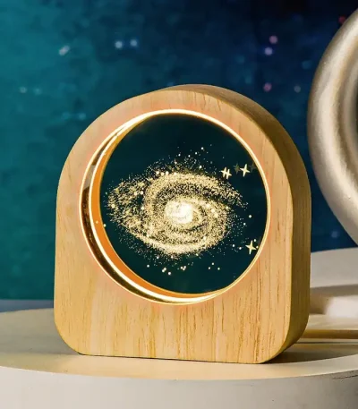 Sternenprojektor mit Galaxie-Design, der einen leuchtenden, spiralförmigen Himmel mit Sternen und Galaxien auf eine Holzbasis projiziert, ideal für Dekoration und wissenschaftliche Inspiration.