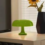 Moderne grüne Tischlampe im Retro-Stil auf einem weißen Tisch, mit Sonnenblume in schwarzer Vase im Hintergrund, ideal für wissenschaftliche Dekorationen.