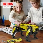Zwei Kinder bauen einen gelben Roboter aus einem 921-teiligen Konstruktionsset, das auf einem Tisch liegt, mit Anleitungen im Hintergrund.