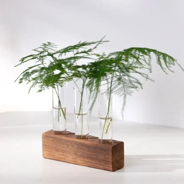 Elegante Blattdekoration mit drei Glasvasen auf einem rechteckigen Holzsockel, ideal für moderne Raumgestaltung und wissenschaftliche Dekoration.