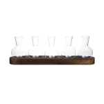 Fünf klare Gläser auf einem dunklen Holzbrett, ideal für wissenschaftliche Experimente oder als dekoratives Element.