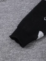 Nahaufnahme eines schwarzen Socken mit wissenschaftlichem Muster auf grauem Stoffhintergrund, detailreiche Textur sichtbar.