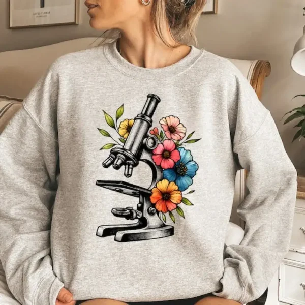 Mikroskop illustriert mit bunten Blumen auf einem grauen Pullover, kombiniert Wissenschaft und Natur in einem modernen und trendigen Stil.