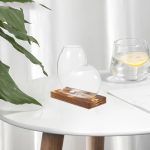 Moderne Glasvase auf Holzsockel, stilvoll dekoriert, ideal für Wohnraumgestaltung.