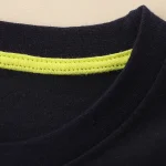 Nahaufnahme eines schwarzen T-Shirts mit einem neon-grünen Nackenstreifen, ideal für wissenschaftliche Dekorationen oder als modisches Statement.