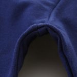 Nahaufnahme eines dunkelblauen Baumwoll-Hoodies, Fokus auf die Stoffstruktur und den Saum, detailreiche Textur und weiche Oberfläche sichtbar.