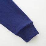 Nahaufnahme eines blauen Hoodie-Ärmels mit Bündchen, detailreiche Textur und Stoffqualität sichtbar. Perfekt für Mode- und Bekleidungsfotos.