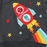 Bunte Raketen-Applikation mit Dinosaurier-Design, ideal für Kinderkleidung oder Dekorationen, gefertigt aus Stoff mit bunten Details und Flammen.