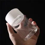 Transparentes Glas mit weißem Deckel, gehalten in einer Hand gegen schwarzen Hintergrund.