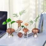 Dekorative Glasvasen in Pilzform mit grünen Pflanzen, ideal für moderne Raumgestaltung und als wissenschaftliche Dekoration.
