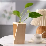 Blumen in einer stilvollen, modernen Holzvase auf einem weißen Tisch. Perfekt für wissenschaftliche Dekorationen und elegante Raumgestaltung.